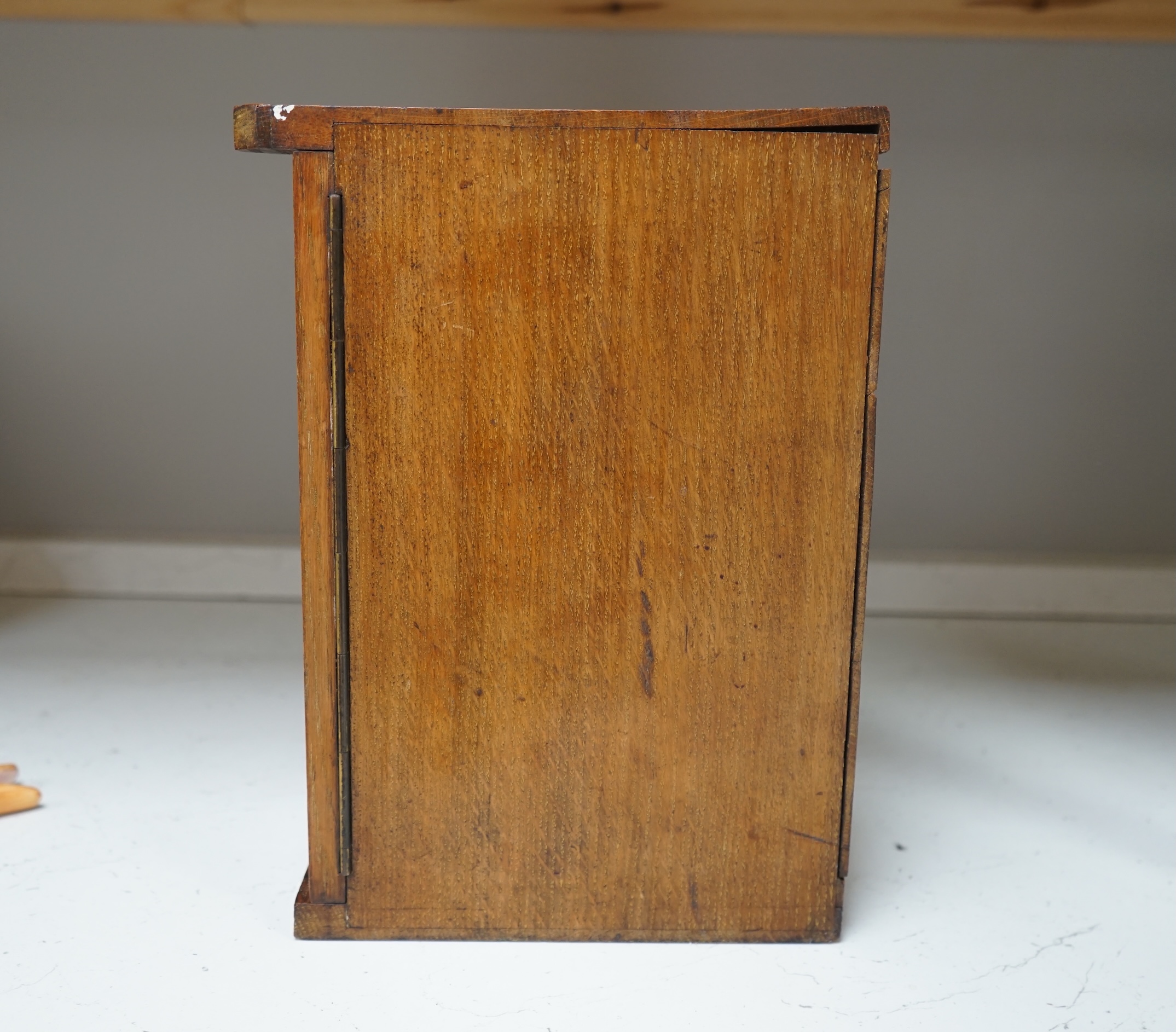 A Victorian oak cigar cabinet modelled as a safe, with brass coat of arms mounts, 30cm wide, 31cm high. Condition - fair